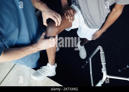 Aus der Sicht eines männlichen Arztes, der das Bein des Patienten während des Trainings im Fitnessstudio massiert Stockfoto