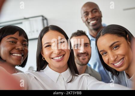 Halten Sie inne und lächeln Sie. Eine Gruppe von Kollegen, die in einem Büro ein Selfie machen. Stockfoto