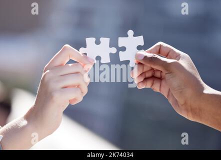 Kombinierter Kraftaufwand sorgt für eine perfekte Passform. Zwei nicht erkennbare Geschäftsleute vervollständigen ein Puzzle. Stockfoto