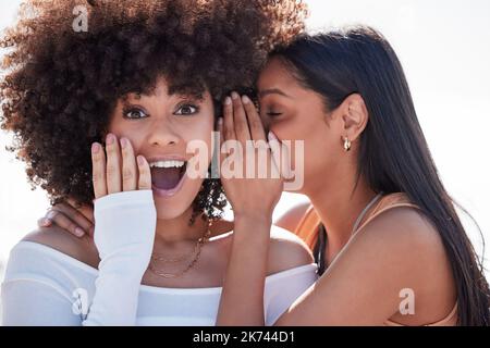 Die Nachricht an ihre Bestie zu verbreiten. Eine junge Frau flüstert ihren Freunden ins Ohr, während sie an der Promenade hängt. Stockfoto