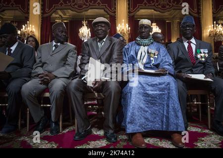 Der französische Präsident Francois Hollande überreicht einem senegalesischen Veteranen während einer Zeremonie, bei der er die französische Staatsbürgerschaft an ehemalige senegalesische Kriegsveteranen im Elysee-Palast vergibt. Stockfoto