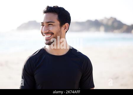 Ich liebe es hier draußen zu sein. Ein hübscher junger Athlet, der beim Sport am Strand nachdenklich aussieht. Stockfoto