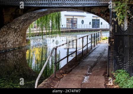 Eine Frau geht entlang des Regent Canal Towpath unter der Camden Road Bridge, London, Großbritannien Stockfoto