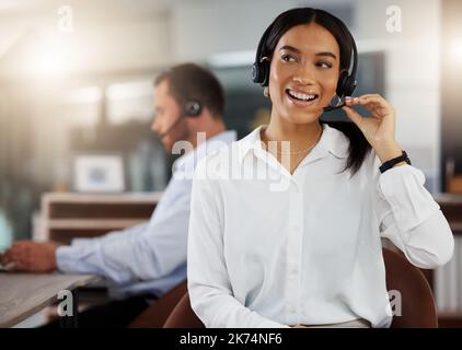 Ihre freundliche Art wird sehr geschätzt. Ein junger Call Center-Agent, der nachts in einem Büro arbeitet. Stockfoto