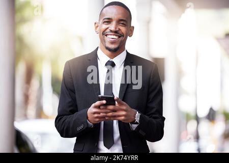 Ihr könnt mich immer erreichen. Beschnittenes Porträt eines hübschen jungen Geschäftsmannes, der seine Nachrichten während seines morgendlichen Arbeitsbeginns überprüft. Stockfoto