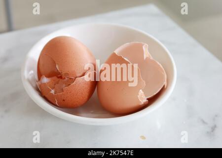 Eierschalen in einer weißen Schale auf dem Tisch Stockfoto