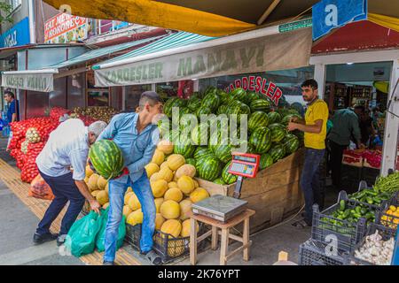 KARS, TÜRKEI - 18. JULI 2019: Arbeiter werfen und fangen Melonen in einem Obst- und Gemüseladen in Kars, Türkei Stockfoto