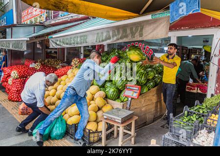 KARS, TÜRKEI - 18. JULI 2019: Arbeiter werfen und fangen Melonen in einem Obst- und Gemüseladen in Kars, Türkei Stockfoto