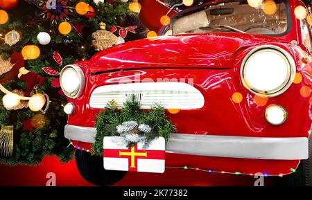 Das rote Neujahrsauto mit der Flagge von Guernsey vor dem Hintergrund eines farbenfrohen Weihnachtshintergrunds Stockfoto