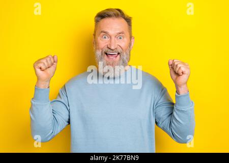 Porträt der erfreut überglücklich Person heben Fäuste Glück Triumph Erreichung isoliert auf gelbem Hintergrund Stockfoto