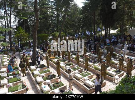 Ein israelischer Soldat sitzt an den Gräbern gefallener Soldaten im Mt. Herzl Militärfriedhof in Jerusalem, zum Gedenktag für Soldaten und Terror-Opfer, 8. Mai 2019. Tausende von Israelis versammelten sich auf MilitärFriedhofs im ganzen Land, um an 23.741 Soldaten und 3.150 Terroropfer zu erinnern. Stockfoto