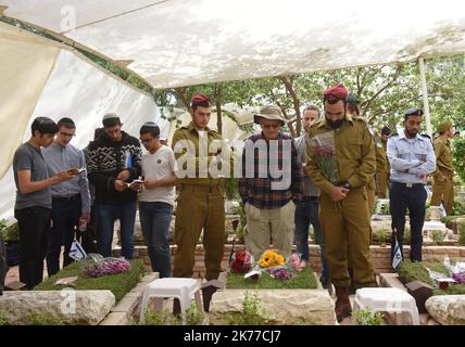 Ein israelischer Soldat sitzt an den Gräbern gefallener Soldaten im Mt. Herzl Militärfriedhof in Jerusalem, zum Gedenktag für Soldaten und Terror-Opfer, 8. Mai 2019. Tausende von Israelis versammelten sich auf MilitärFriedhofs im ganzen Land, um an 23.741 Soldaten und 3.150 Terroropfer zu erinnern. Stockfoto
