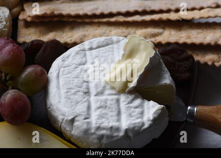 Ein Rad aus Brie-Käse mit violetten Trauben und Crackern Stockfoto