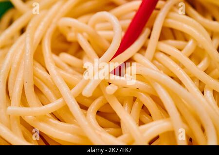 Bio-Grieß-Pasta wird in einer kleinen Schale mit roten Chapsticks über einem roten Küchetücher serviert Stockfoto