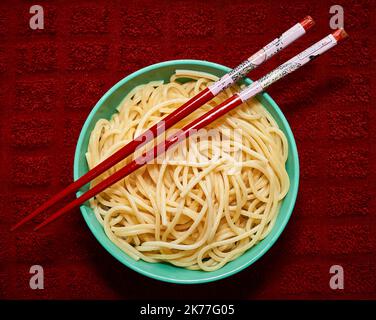 Bio-Grieß-Pasta wird in einer kleinen Schale mit rotem Chapstick über einem roten Küchetücher serviert Stockfoto