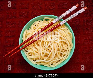 Bio-Grieß-Pasta wird in einer kleinen Schale mit rotem Chapstick über einem roten Küchetücher serviert Stockfoto