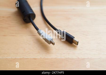 Mehrere Ladekabel liegen auf einem Tisch, darunter USB A 2,0 sowie USB C- und AV-Kabel Stockfoto