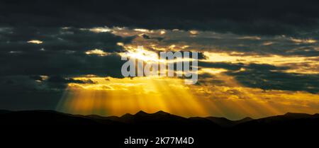 Lichtstrahlen, die durch stürmische Wolken scheinen und dramatische Sonnenuntergänge abdecken. Stockfoto