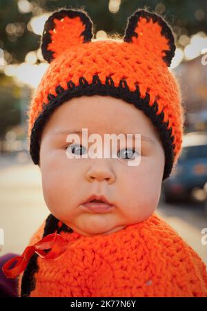 Ein Baby trägt ein einzigartiges Kostüm Oma aus buntem Garn Stockfoto