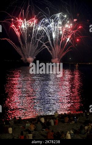 Am Vorabend des Bastille-Tages, am 13. Juli 2019, neben der Promenade des Anglais in Nizza, sitzen die Menschen am Strand, um ein Feuerwerk am Himmel zu sehen Stockfoto