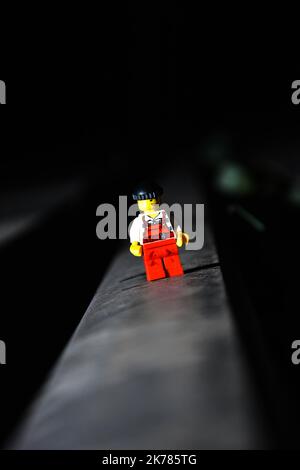 Ein vertikaler Nahaufnahme-Lego-Filmheld, der auf einer schwarzen Oberfläche mit dunklem, unscharfem Hintergrund steht Stockfoto