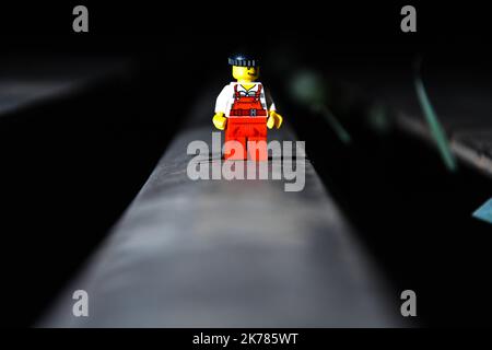 Ein Lego-Filmheld, der auf einer schwarzen Oberfläche mit dunklem, unscharfem Hintergrund steht Stockfoto