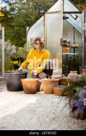 Frau pflanzt Blumen in Krügen im Garten Stockfoto