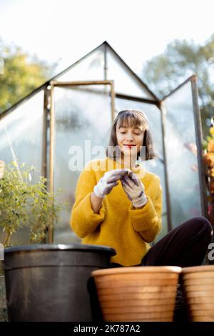 Frau pflanzt Blumen in Krügen im Garten Stockfoto