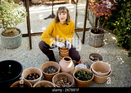 Frau pflanzt Blumen in Krügen im Garten Stockfoto