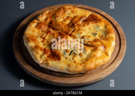 Traditionelles georgisches Brot khachapuri auf Holzbrett auf schwarzem Hintergrund Stockfoto