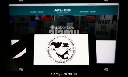 Person mit Mobiltelefon und Logo des US-Gewerkschaftsbundes AFL-CIO auf dem Bildschirm vor der Webseite. Konzentrieren Sie sich auf die Telefonanzeige. Stockfoto