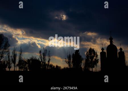 Schwarze Silhouette von Kirche und Friedhof. Ein unheilvoller Blick auf eine schwarze Kirche mit Kuppeln und Kreuzen, einen Kirchenfriedhof und einen dunklen Wald. Alle Heiligen Stockfoto