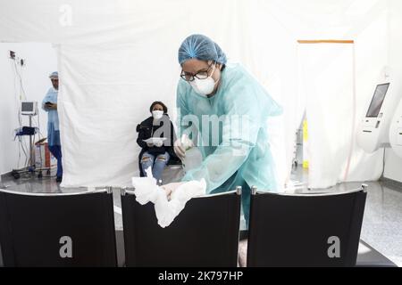 Ein Mitarbeiter des Krankenhauses dekontaminiert die Sitze in einer Coronavirus-Testeinrichtung Stockfoto