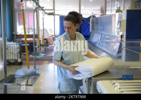 Mitarbeiter, die Wäsche in der Wäscherei des Krankenhauses Emile Muller in Mulhouse verarbeiten Stockfoto