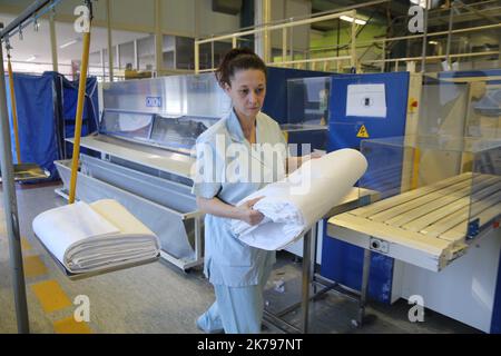 Mitarbeiter, die Wäsche in der Wäscherei des Krankenhauses Emile Muller in Mulhouse verarbeiten Stockfoto