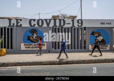 Senegal / Dakar / Dakar - Jugendliche passieren vor Graffiti an der Universität Dakar, um auf Hygienemaßnahmen im Kampf gegen den Covid-19 aufmerksam zu machen. Stockfoto