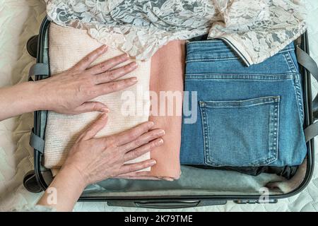 Frau, die Koffer zu Hause packt. Urlaub, Reise, Geschäftsreise. Nahaufnahme von oben Stockfoto