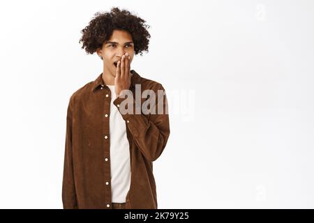 Porträt eines hisptanischen männlichen Studenten, gucken, fühlt sich müde oder gelangweilt, zeigt Gleichgültigkeit, steht auf weißem Hintergrund Stockfoto
