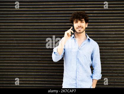 Junger Geschäftsmann, der in einer Stadt telefoniert Stockfoto