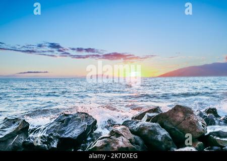 Maui Hawaii bei Sonnenuntergang mit niedriger Sonne, Felsen und einem Berg Stockfoto