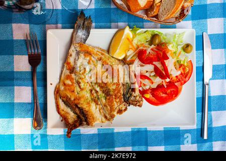 Gebratene dorada mit Pesto, serviert mit Gemüsegarnitur und Zitrone Stockfoto