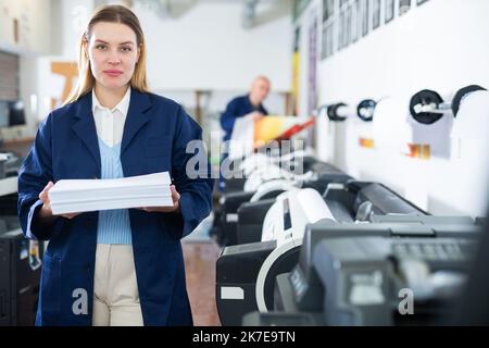 Der Techniker wechselt das Papier auf der Plottermaschine des Druckers Stockfoto