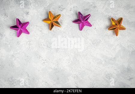 Minimalistischer weihnachtshintergrund mit goldenen und violetten Sternen auf weißem Hintergrund Stockfoto