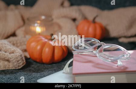 Kleine Kürbisse, kuschelig gestrickt blanked, Notizbuch und Brille auf Sofa Stockfoto