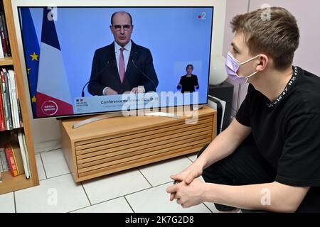 ©PHOTOPQR/L'EST REPUBLICAIN/ALEXANDRE MARCHI ; NANCY ; 27/12/2021 ; SANTE - POLITIQUE - OMICRON - EPIDEMIOLOGIE COVID 19 - CORONAVIRUS - CONFERENCE DE PRESSE PM - 5EME VAGUE - DOSE DE RAPPEL - JAUGE - DOSE DE RAPPEL - PASS SANITAIRE - PASS VACCINAL. Dezember 27 in Nancy 2021. Une personne, portant un masque chirurgical de Protection, regarde et écoute le Premier Ministre Jean CASTEX lors d'une conférence de Presse télévisée à la Suite du conseil de défense sanitaire alors qu'une nouvelle vague de contaminations déferle sur la France et dans le monde entier avec le variant Omicron. FOTO Alexandre MAR Stockfoto