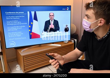 ©PHOTOPQR/L'EST REPUBLICAIN/ALEXANDRE MARCHI ; NANCY ; 27/12/2021 ; SANTE - POLITIQUE - OMICRON - EPIDEMIOLOGIE COVID 19 - CORONAVIRUS - CONFERENCE DE PRESSE PM - 5EME VAGUE - DOSE DE RAPPEL - JAUGE - DOSE DE RAPPEL - PASS SANITAIRE - PASS VACCINAL. Dezember 27 in Nancy 2021. Une personne, portant un masque chirurgical de Protection, regarde et écoute le Premier Ministre Jean CASTEX lors d'une conférence de Presse télévisée à la Suite du conseil de défense sanitaire alors qu'une nouvelle vague de contaminations déferle sur la France et dans le monde entier avec le variant Omicron. FOTO Alexandre MAR Stockfoto