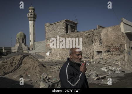 ©Christophe Petit Tesson/MAXPPP - 23/11/2021 ; MOSUL ; IRAQ - UN homme fume une cigarette devant sa maison dans un quartier en rekonstruktion sur les bords du fleuve Tigre. La ville de Mossoul, Liberee de l'Etat Islamique en Juillet 2017, a subi d'importantes destructions urbaines et se releve Petit a Petit avec l'aide de projeets internationaux sous l'egide de l'UNESCO. Ein Mann raucht eine Zigarette vor seinem Haus in einem Viertel der Altstadt von Mosul, das gerade umgebaut wird. Die Stadt Mosul, die im Juli 2017 vom Islamischen Staat befreit wurde, hat erhebliche städtische Zerstörung erlitten und ich Stockfoto