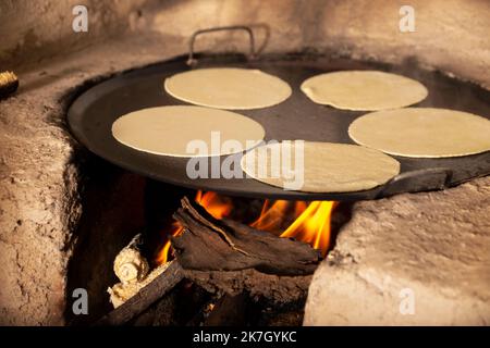 Handgemachte Maistortillas, die in einem traditionellen rustikalen Holzofen namens „fogon“ gekocht werden, eine Art von Kochen, die in ländlichen Gemeinden in Mexiko und anderen Ländern üblich ist Stockfoto