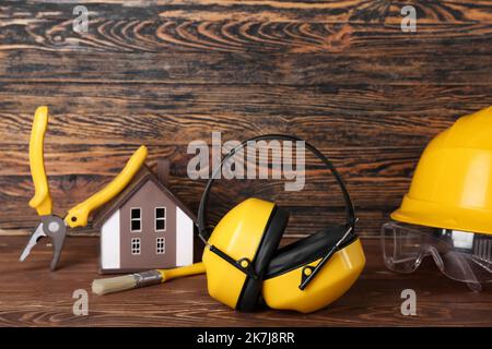 Gehörschutz mit Bauwerkzeugen auf dunklem Holzhintergrund Stockfoto