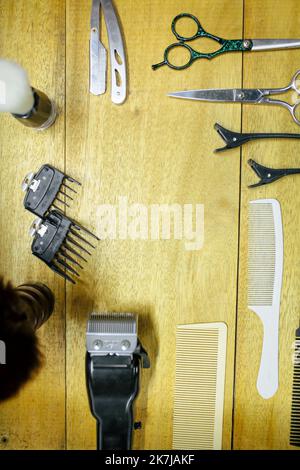 Draufsicht verschiedener professioneller Friseurwerkzeuge auf schwarzem Hintergrund. Stockfoto